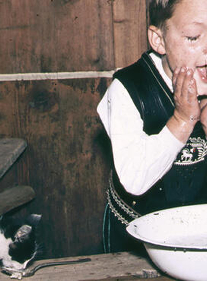 Bub in Tracht mit Schokolade im Gesicht am Waschbecken
